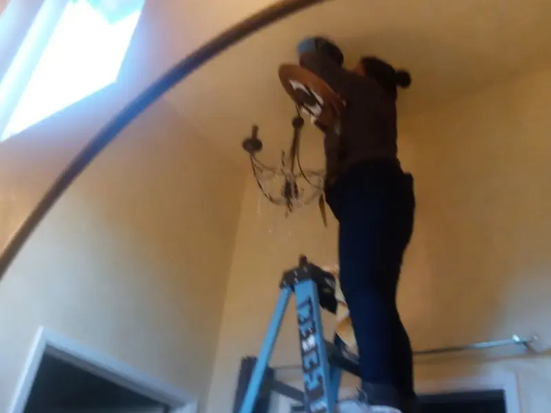 Electrician installing a chandelier in a Park Center residence